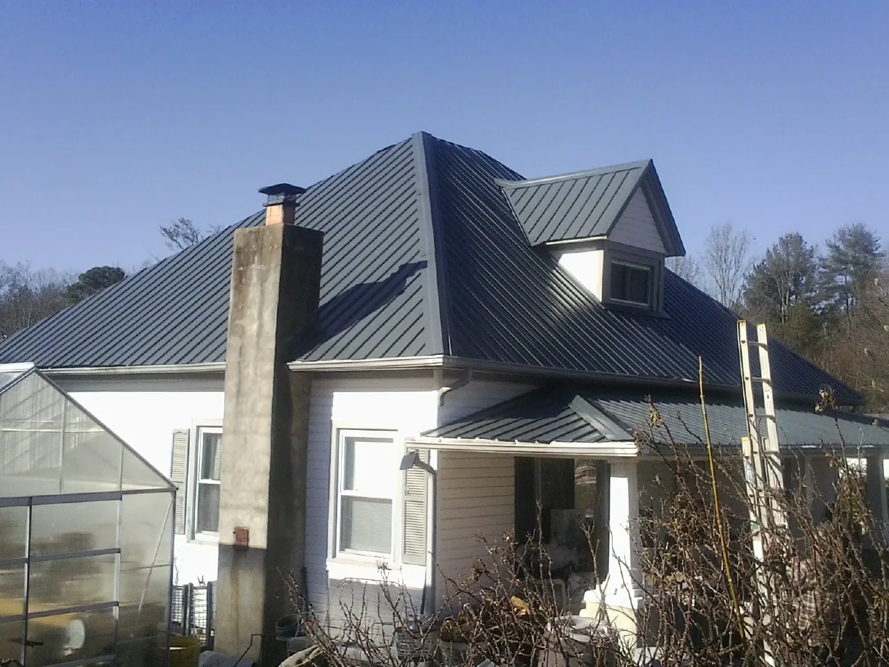 Dark blue standing seam metal roof on a white farmhouse with dormer — Slate & Tile Roof Repair by Roofing Brothers in Crockett