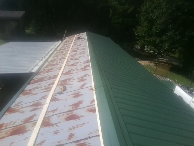 Old rusted panels beside newly installed green metal roofing — Wind Damage Roof Repair by Roofing Brothers in Crockett