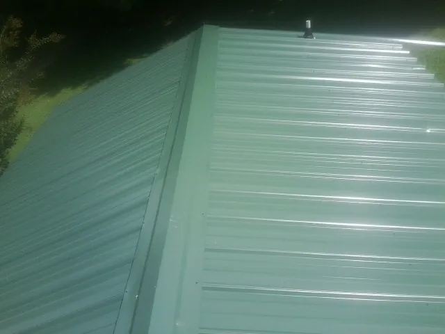 New green metal panels meeting at the ridge of a roof — Flat Roof Repair work by our crew in Crockett