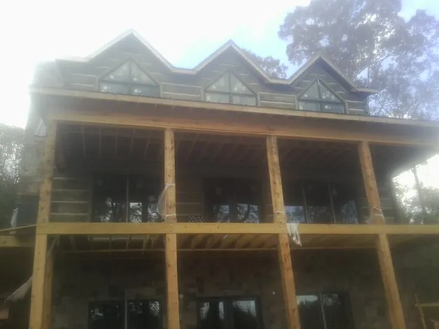 Dormers and porch framing on a large log home under construction — Roof Coating work by our crew in Crockett