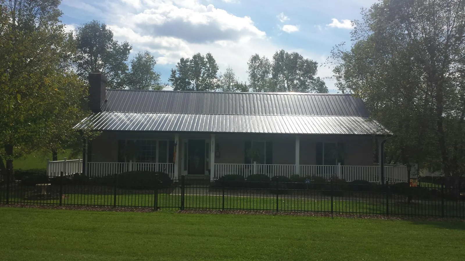 Gray metal roof on a brick ranch with a full width front porch — Gutter Guard Installation work by our crew in Crockett