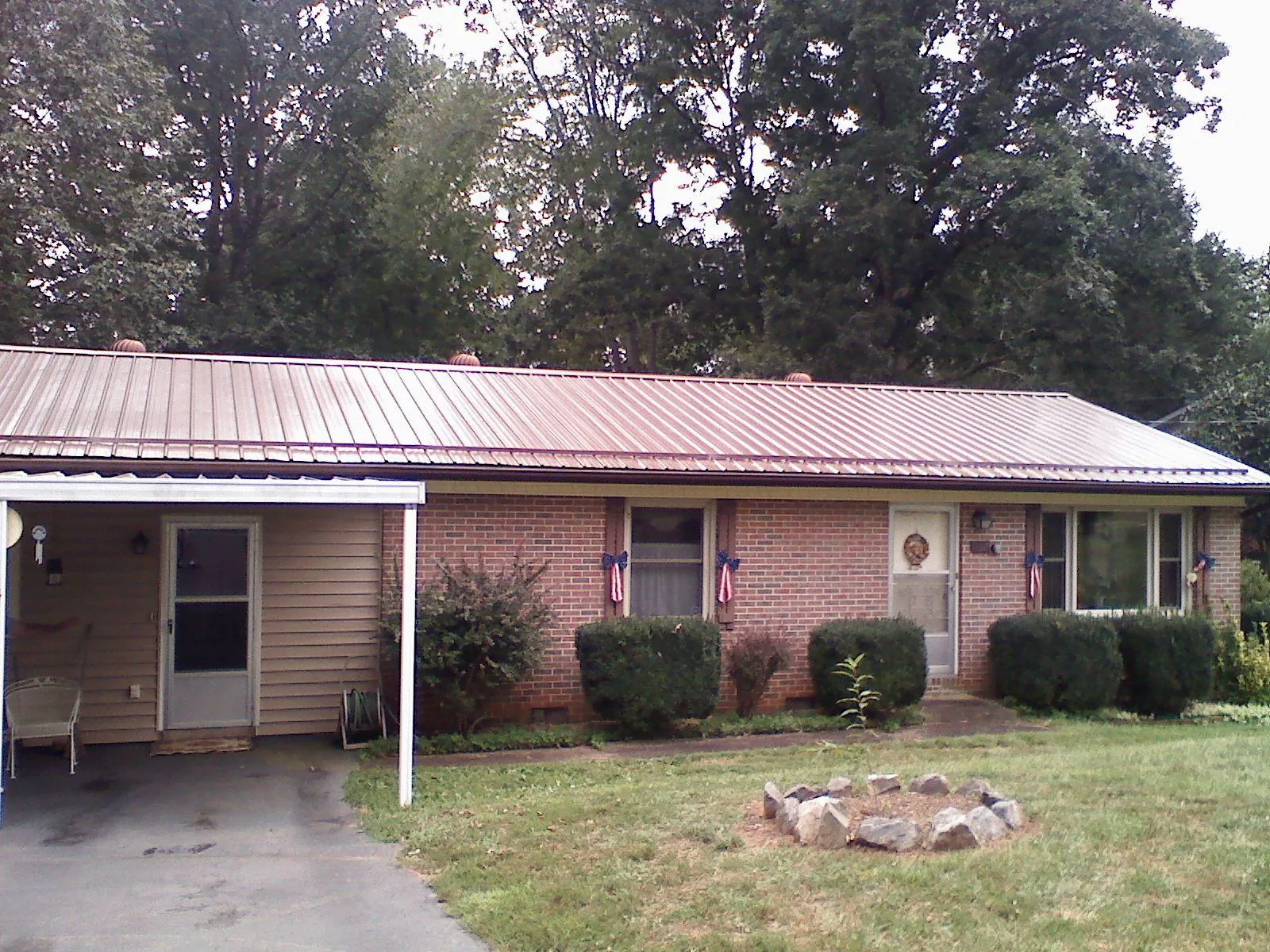 Bronze metal roof and carport on a brick ranch home — Roof Repair work by our crew in Crockett